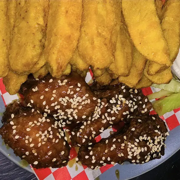 Alitas glaseadas con ajonjolí junto a papas gajo